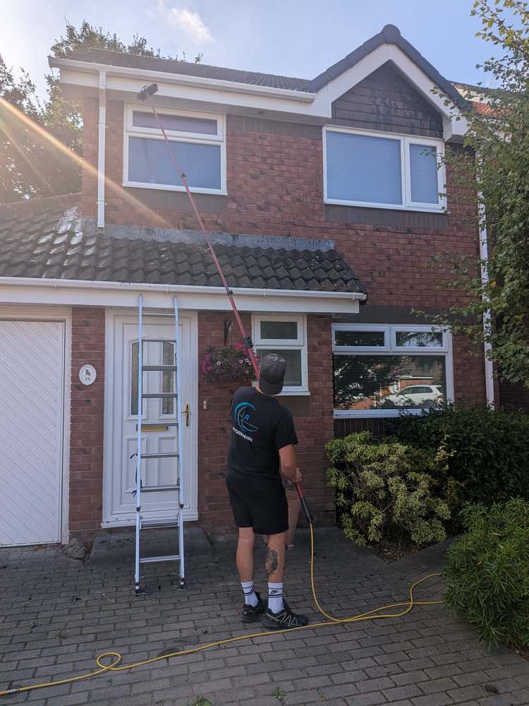 J R Window Cleaning cleaning the upstairs windows of a customer's house with a water-fed pole